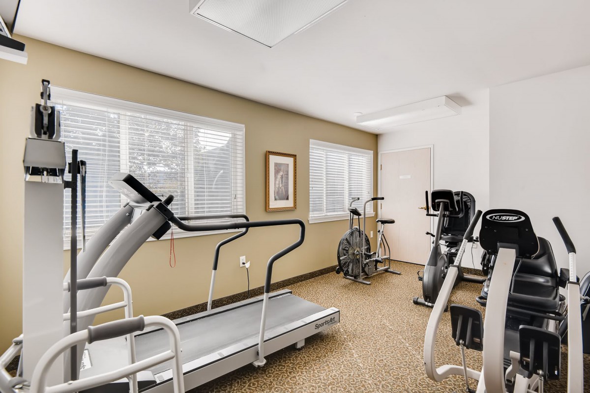 A small gym with various fitness equipment, including a treadmill and an exercise bike.