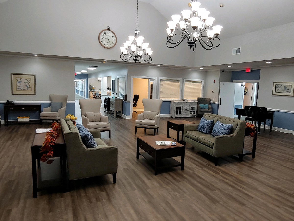 A spacious lobby area with comfortable sofas and chairs, illuminated by elegant chandeliers.