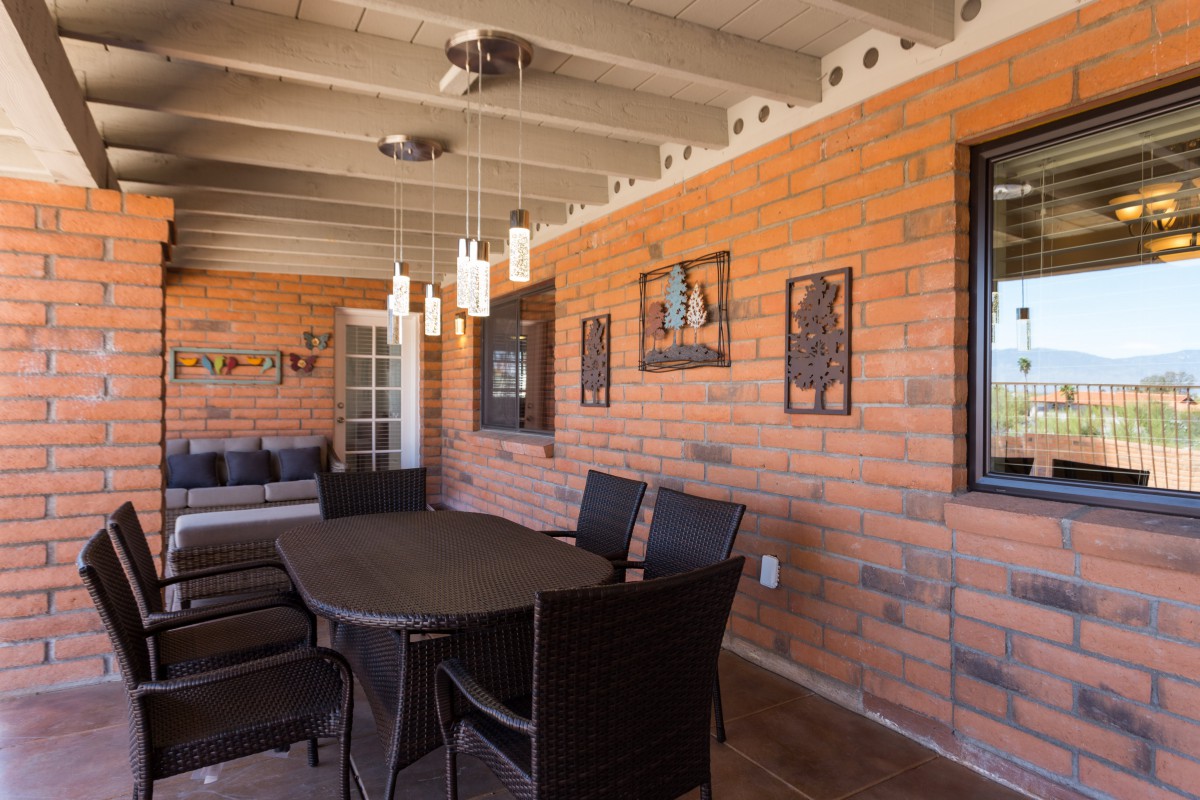 A cozy outdoor dining area with brick walls, modern pendant lighting, and comfortable seating.
