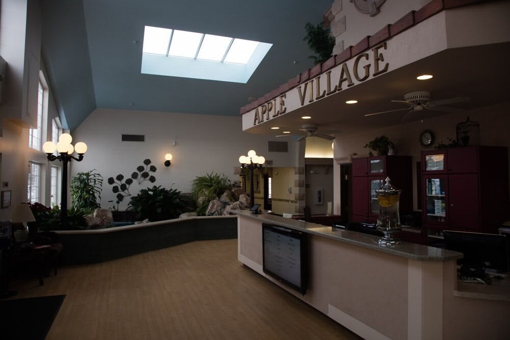 A spacious lobby area with a reception counter, skylight, and decorative plants.