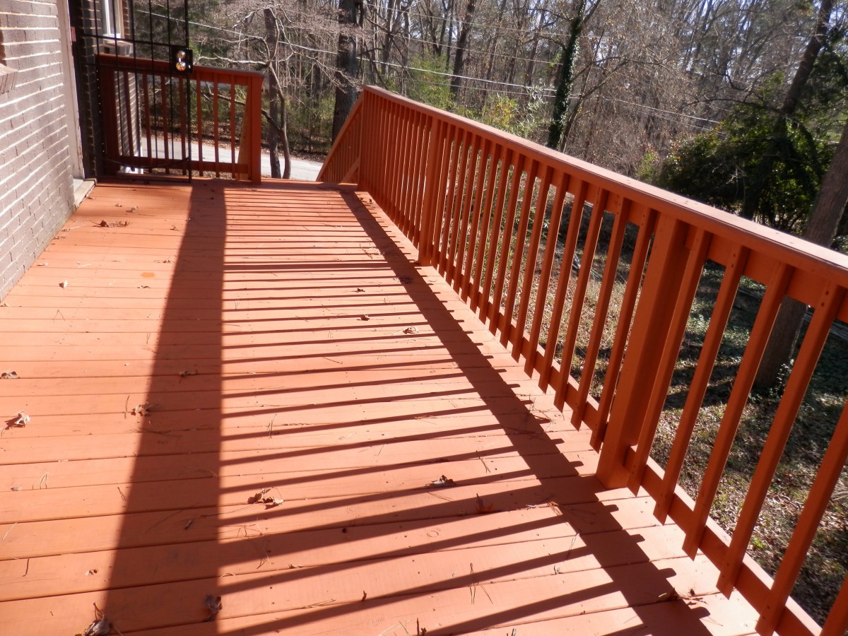 A wooden deck with railings casts long shadows in the sunlight.