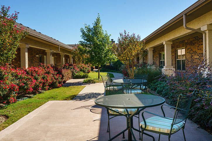 A peaceful outdoor patio area with tables, chairs, and a landscaped garden path.
