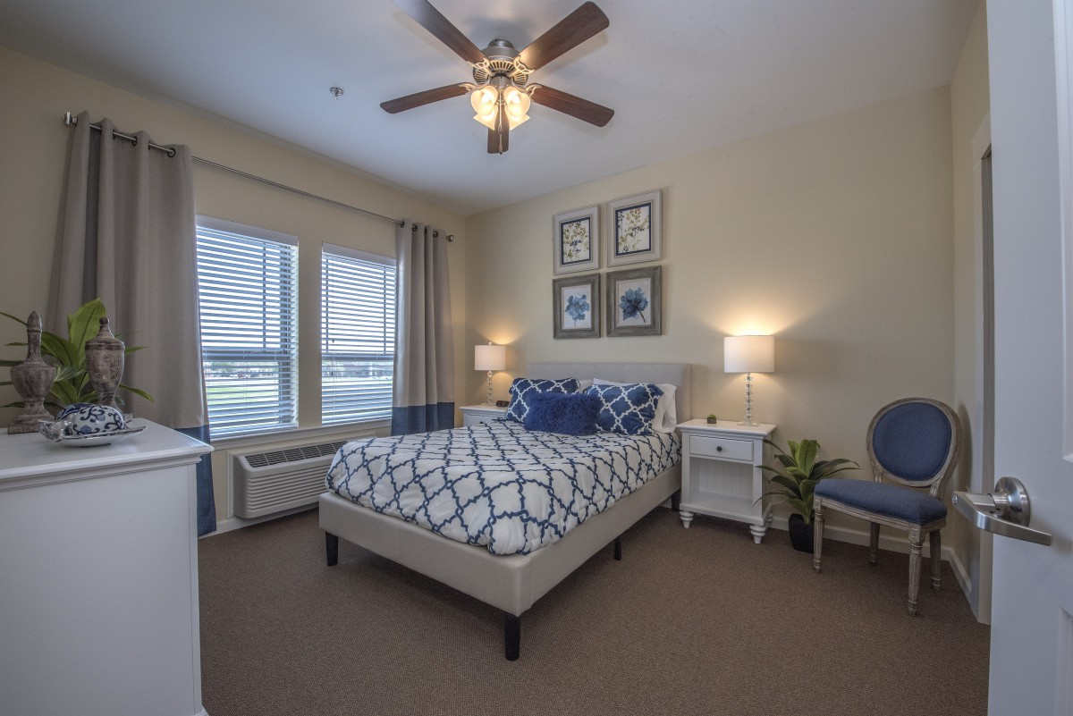 A modern bedroom featuring a neatly made bed, nightstands with lamps, and a ceiling fan, creating a cozy ambiance.