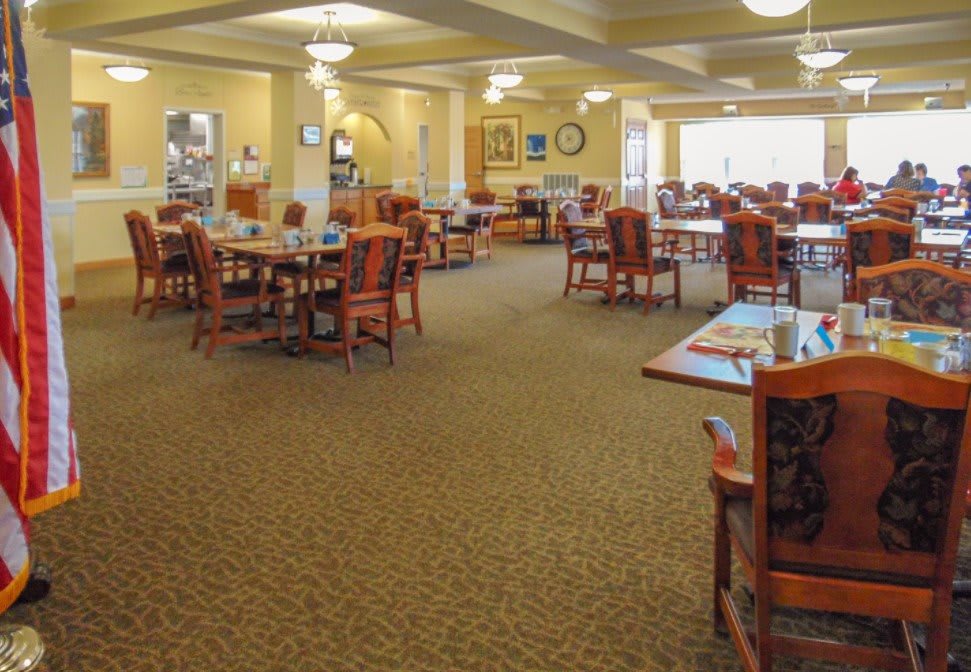 A spacious dining room with neatly arranged tables and chairs under warm lighting.