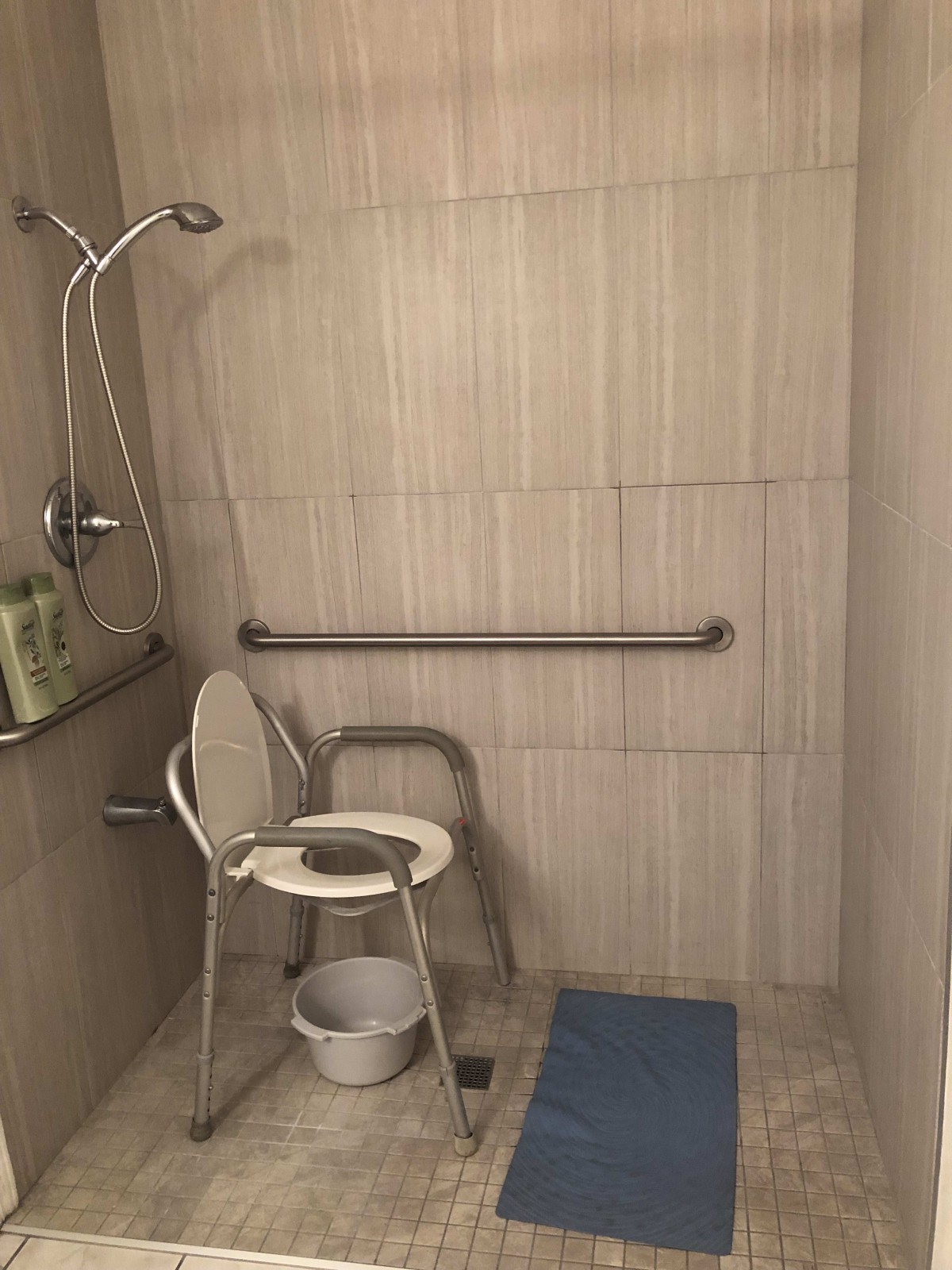 Accessible shower area with a chair and grab bars.
