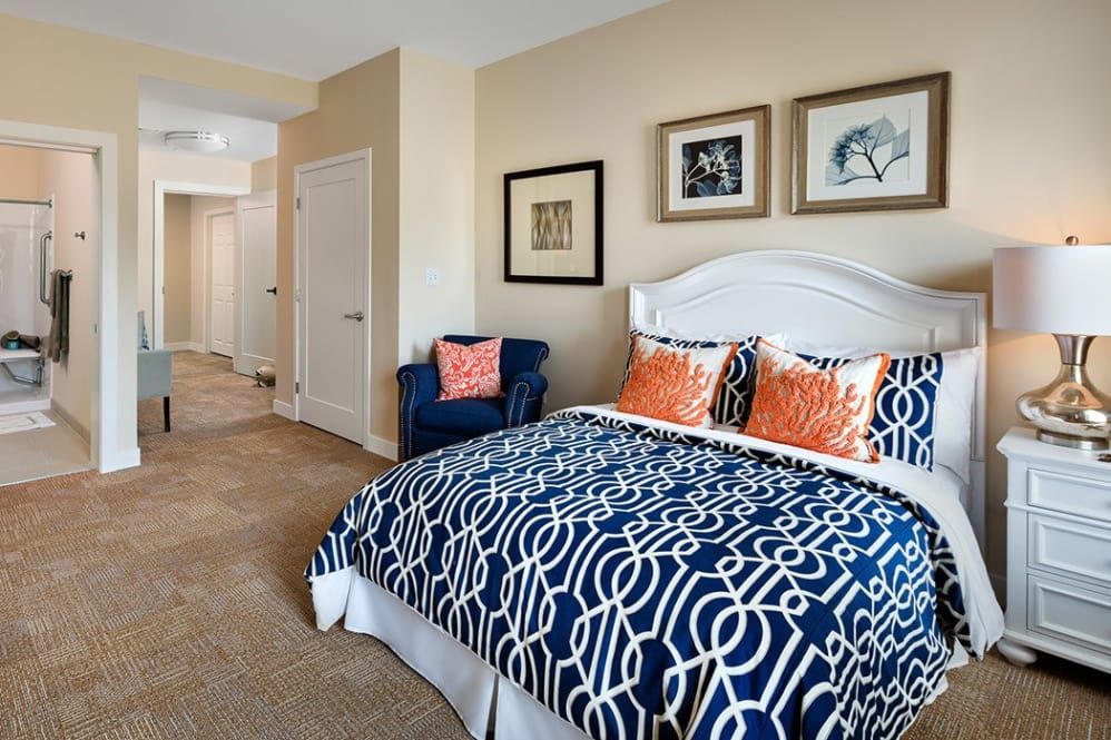 A modern bedroom with stylish bedding and framed artwork on the walls.
