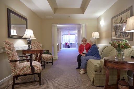 Two people sit and converse in a warmly lit living room.