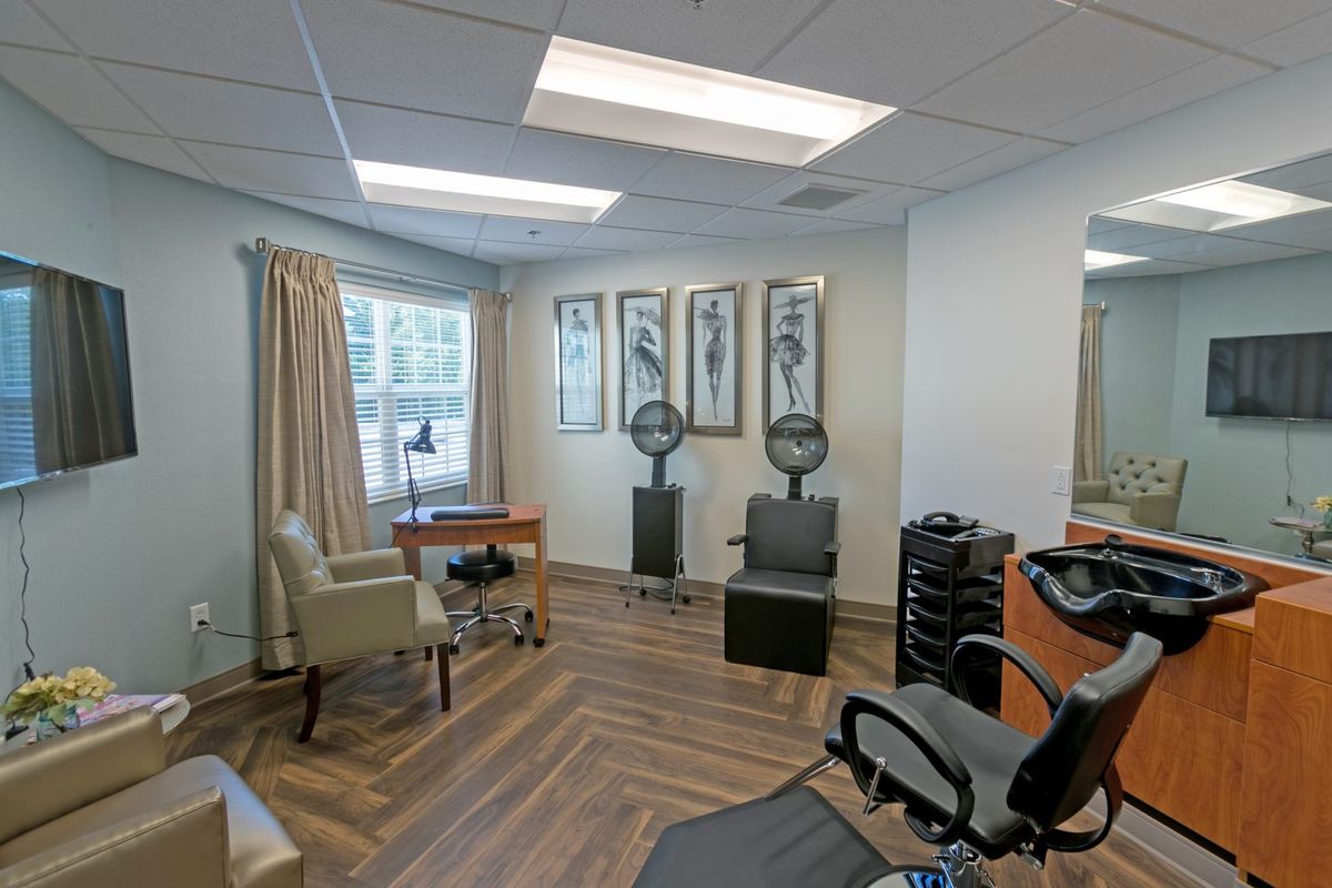 An interior view of a hair salon with chairs, hair dryers, and wooden flooring.