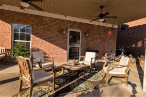 A cozy outdoor patio with comfortable seating and decorative rugs.
