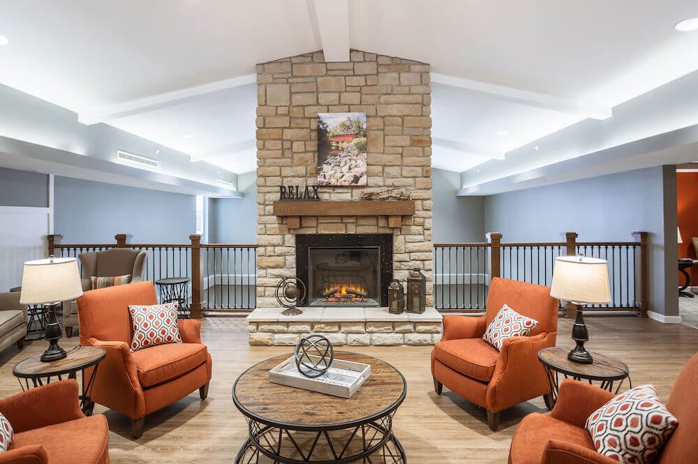 A cozy living room with a stone fireplace and orange armchairs.