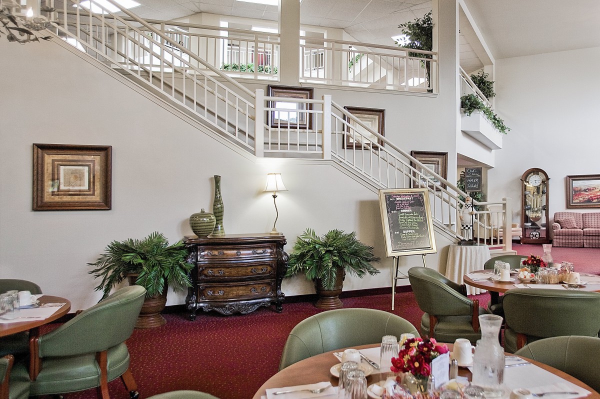 A well-decorated lobby area with a staircase, dining setup, and plants.