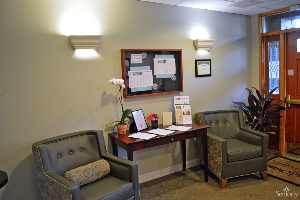 A cozy waiting room with two chairs, a table, and a bulletin board on the wall.