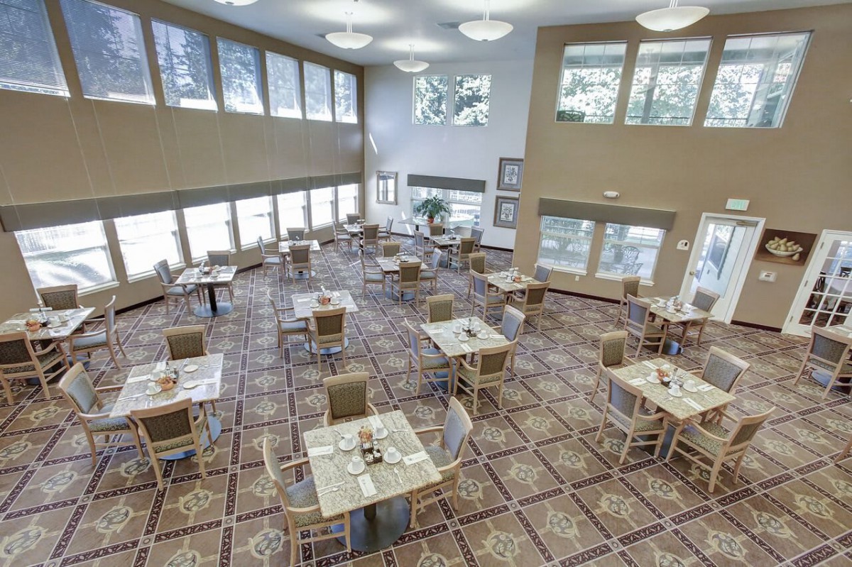 A spacious and modern dining area with multiple tables and large windows allowing natural light to fill the space.