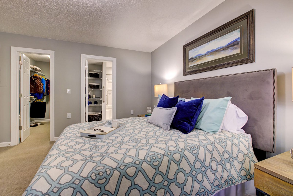 Cozy bedroom with decorative pillows and modern artwork.