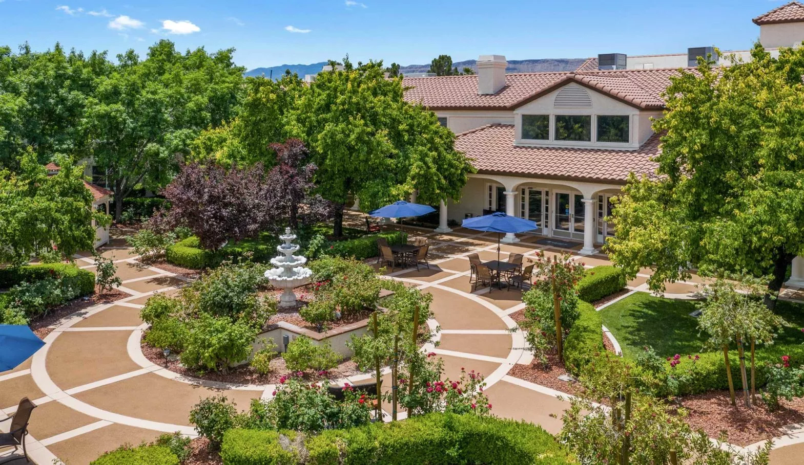 A beautifully landscaped garden with a fountain and outdoor seating area next to a large building.