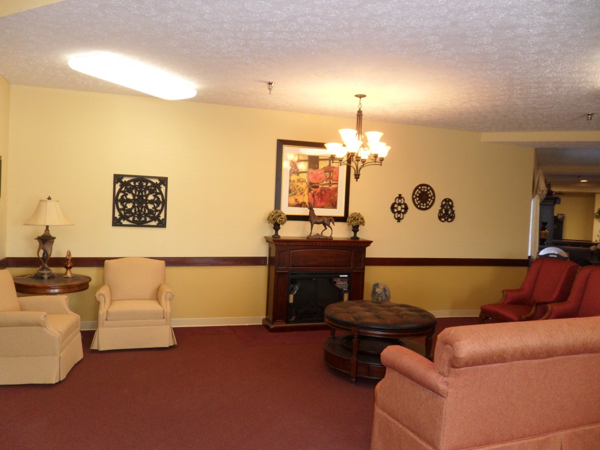 A cozy living room with sofas and armchairs, decorated with art pieces and a chandelier.