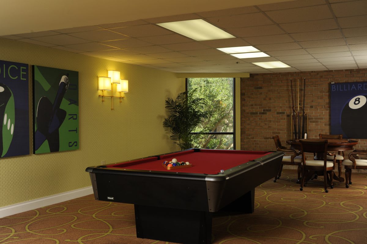 A cozy game room featuring a pool table with red felt and warm lighting.
