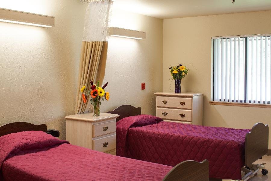 A cozy bedroom with two beds covered in red bedding and decorated with vases of flowers on the dressers.