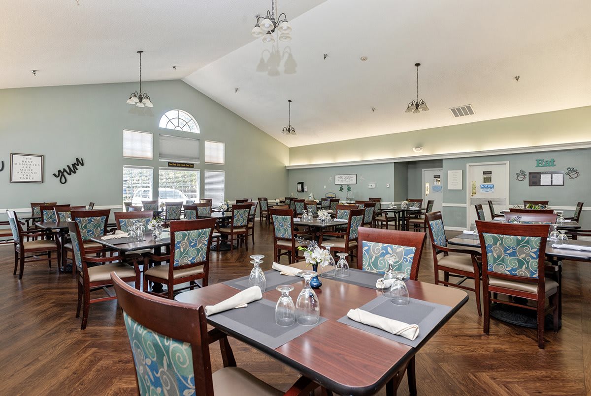 A spacious dining room with neatly arranged tables and chairs, featuring elegant decor and large windows.