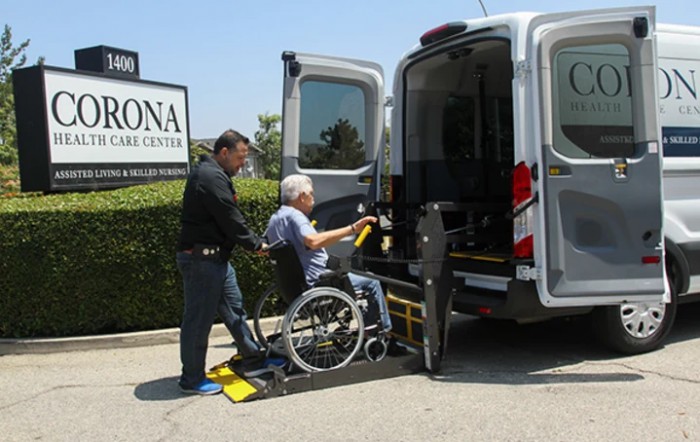 A person in a wheelchair being assisted onto a van using a lift ramp.