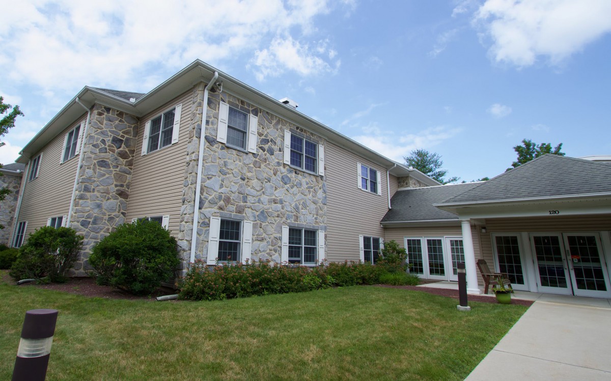 A two-story residential house with a stone facade and well-kept lawn.