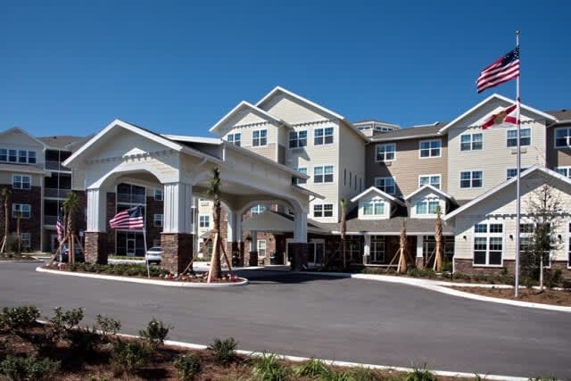 A large residential or hotel building with an entrance driveway and landscaped surroundings.