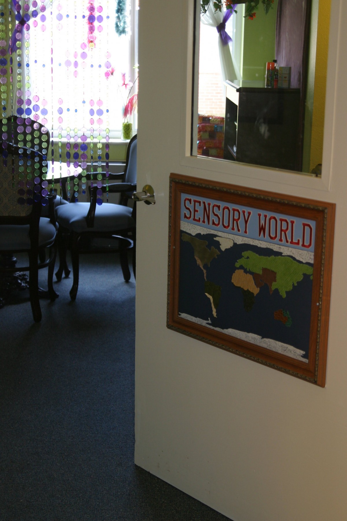 A room labeled 'Sensory World' with a map on the door leading into a space containing chairs.