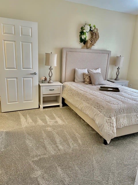A cozy and well-decorated bedroom with a neatly made bed, flanked by two lamps on nightstands.