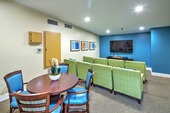 A modern living room with green chairs and a flat-screen TV.