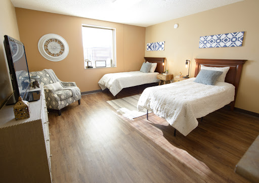 A spacious and well-lit bedroom featuring two beds and a cozy seating area.