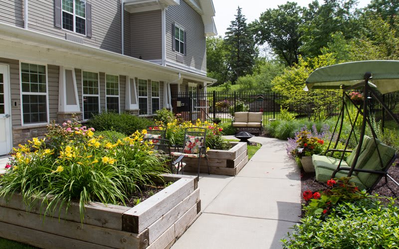 A beautifully landscaped garden with raised flower beds and a paved walkway.
