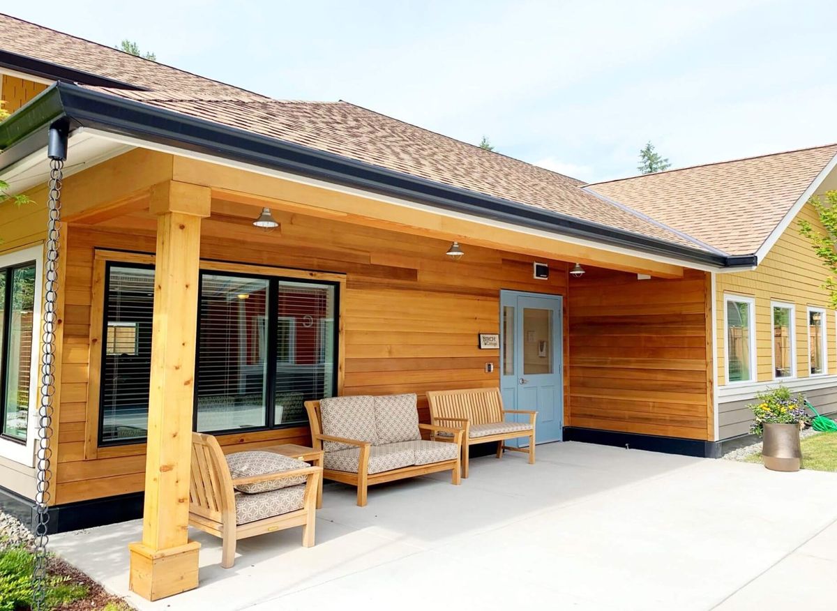 A modern wooden building with a cozy patio area featuring outdoor seating.