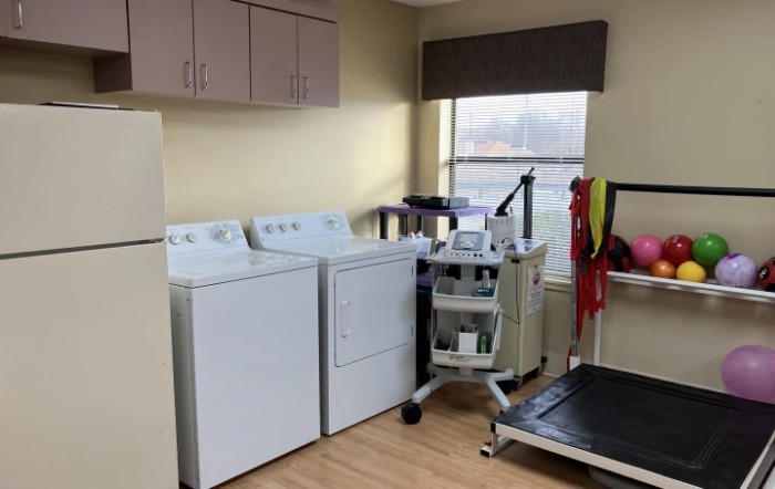 A room featuring washing machines, a dryer, and medical equipment including a treadmill.