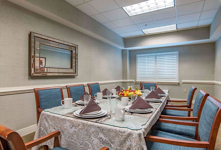 A neatly arranged dining room with a table set for a meal, featuring plates, cups, and folded napkins.