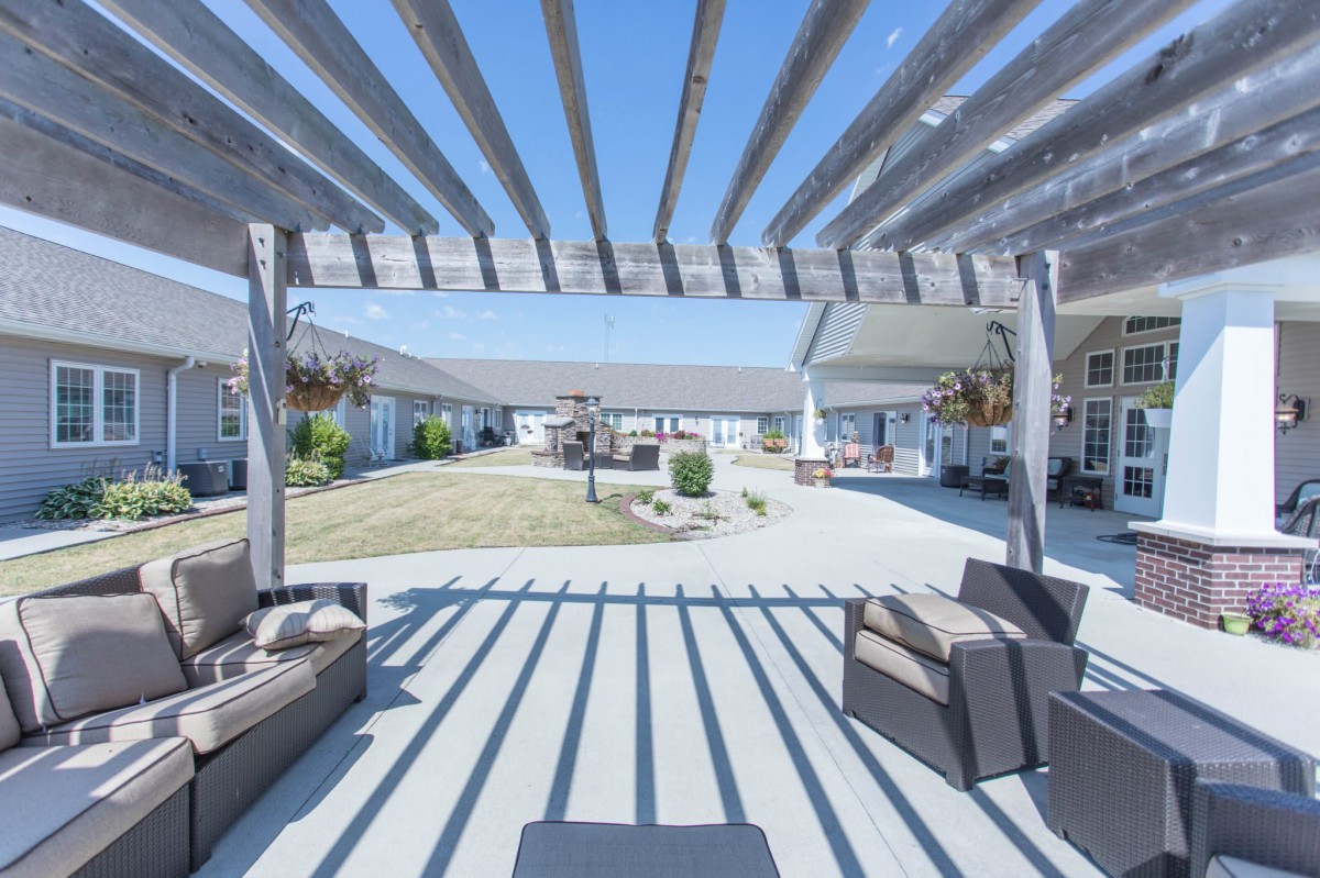 A sunny patio area with a pergola casting strong shadows over outdoor seating.