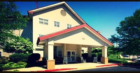 A sunny view of a building entrance with a red roof and columns.