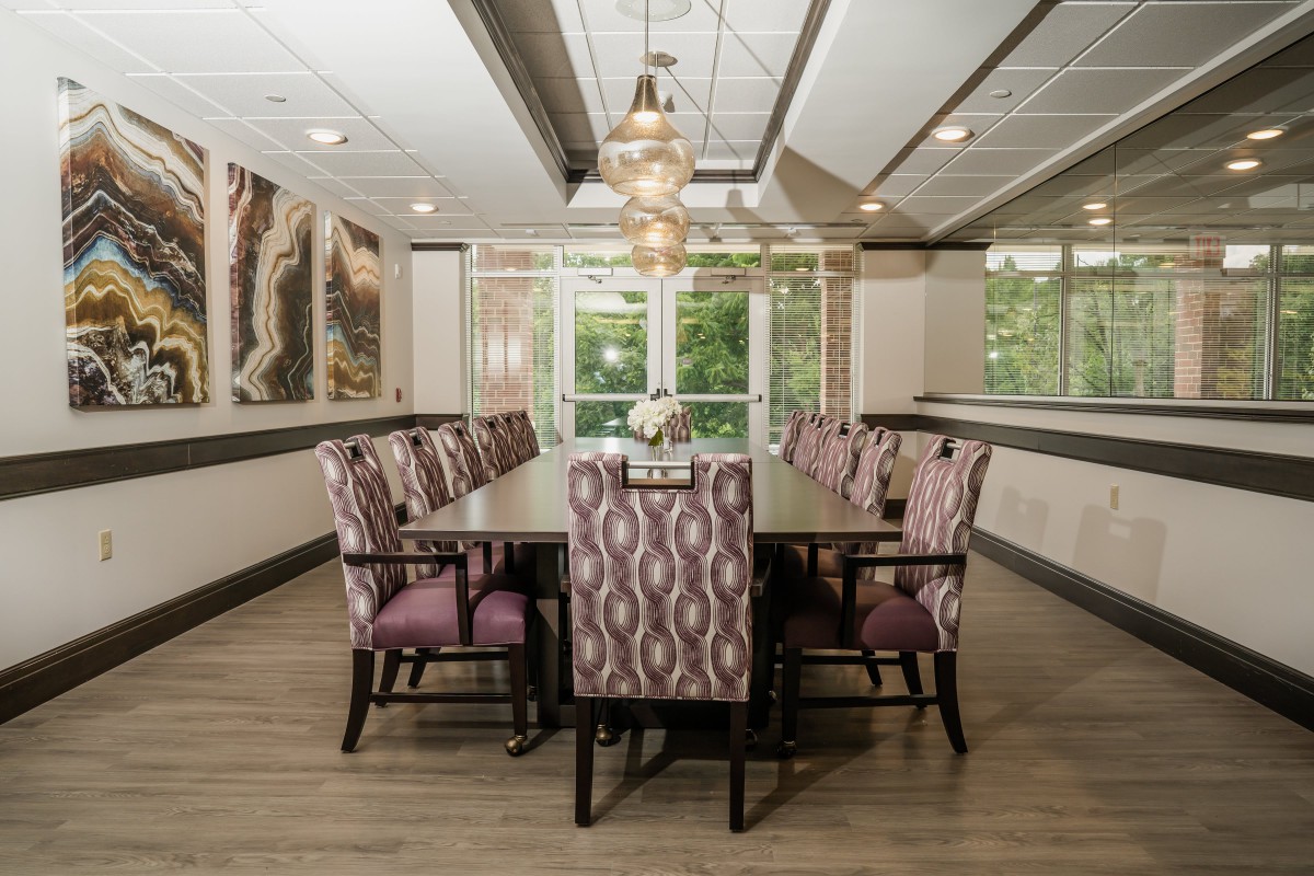 A modern dining room with elegant chairs and a stylish chandelier, featuring large windows for natural light.