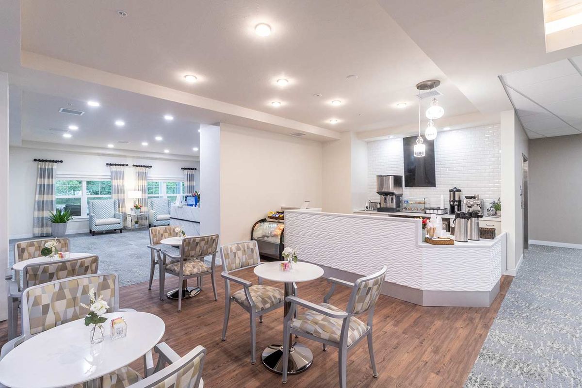 A modern cafe interior with tables, chairs, and a coffee station.