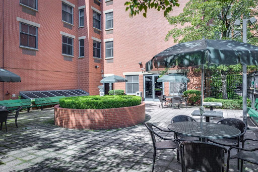 A serene courtyard featuring outdoor seating surrounded by greenery and a modern building backdrop.