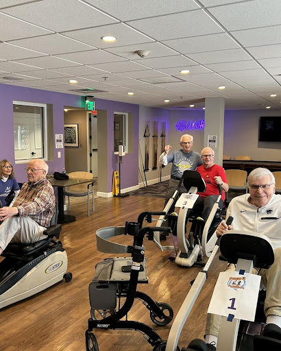 Elderly individuals participating in a group exercise session on stationary bikes.