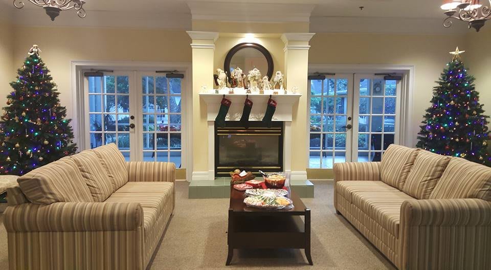A cozy living room with a fireplace, two sofas, and a coffee table, beautifully decorated for the holidays.