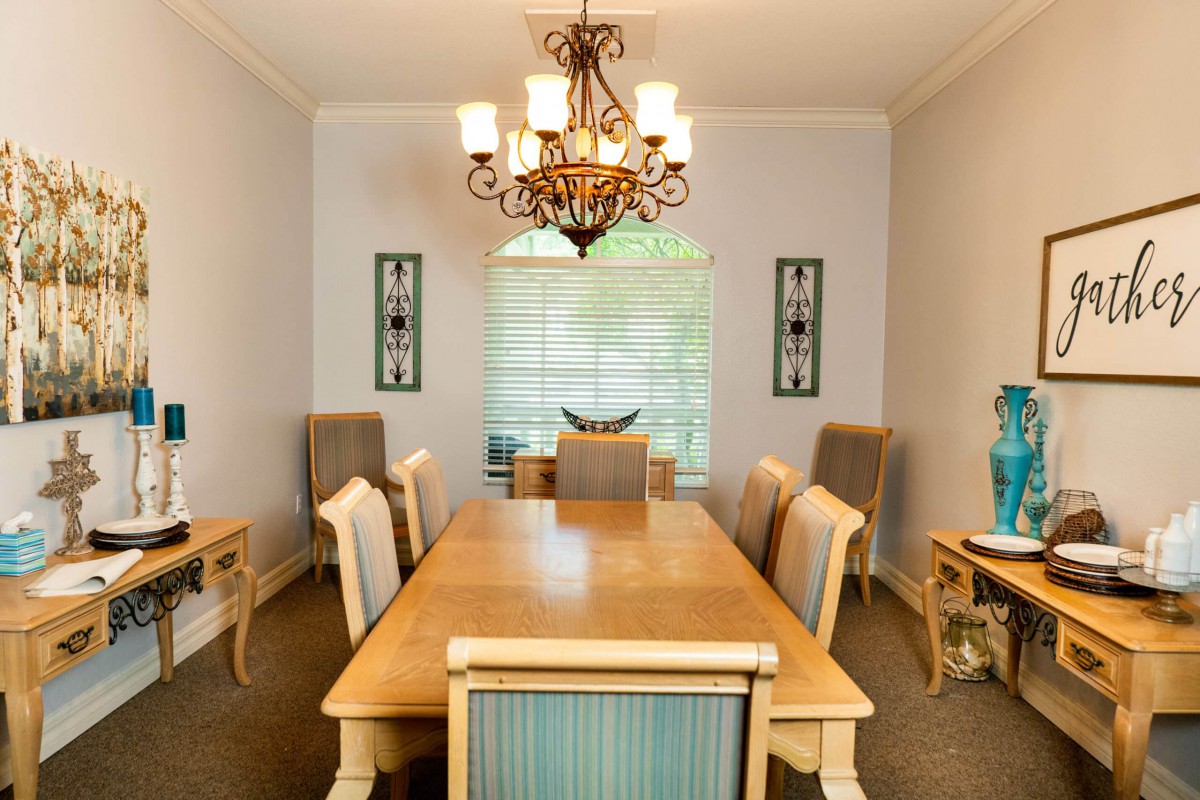 Elegant dining room with a wooden table, upholstered chairs, and a decorative chandelier.