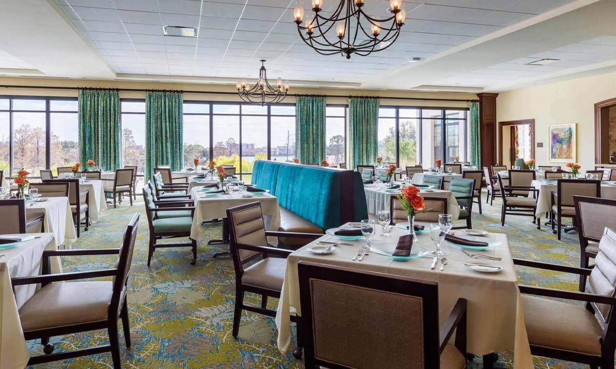 A spacious dining area with elegantly set tables and large windows offering a scenic view.