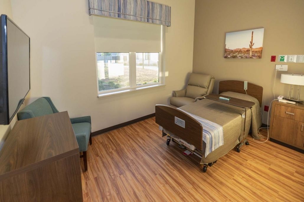 A clean and well-organized hospital room with a bed, chair, and window.