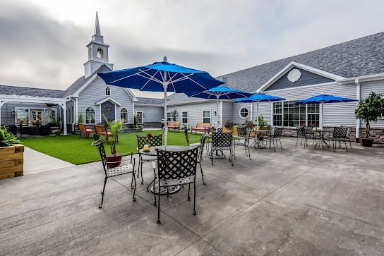 A spacious patio with tables and umbrellas near a church building.