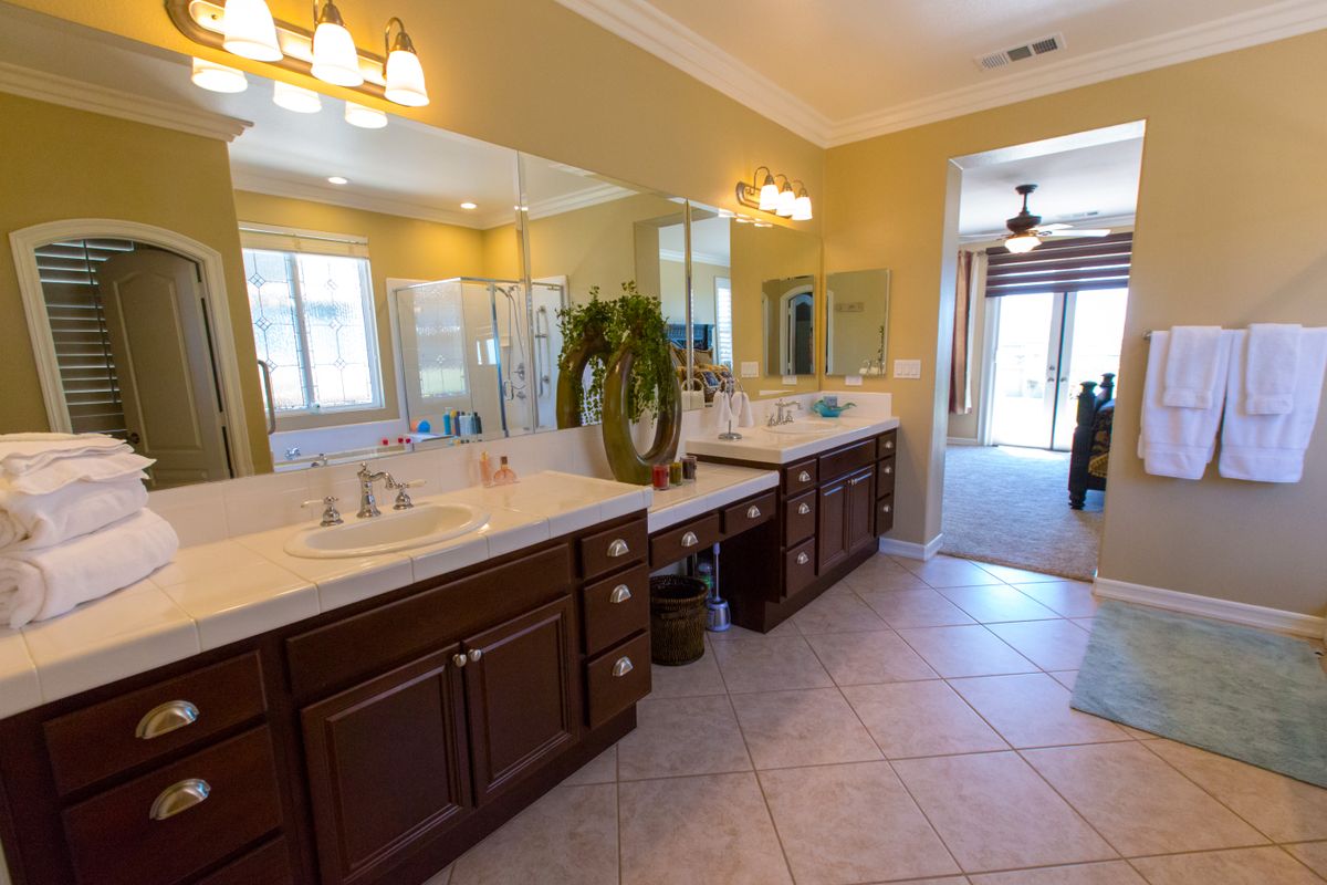 A modern bathroom with a double vanity, large mirrors, and elegant lighting fixtures.