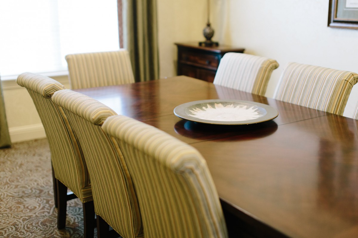 A neatly arranged dining room featuring a wooden table with striped chairs and a decorative centerpiece.
