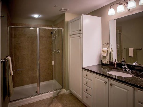 A modern bathroom featuring a glass-enclosed shower, vanity with a sink, and illuminated mirror.