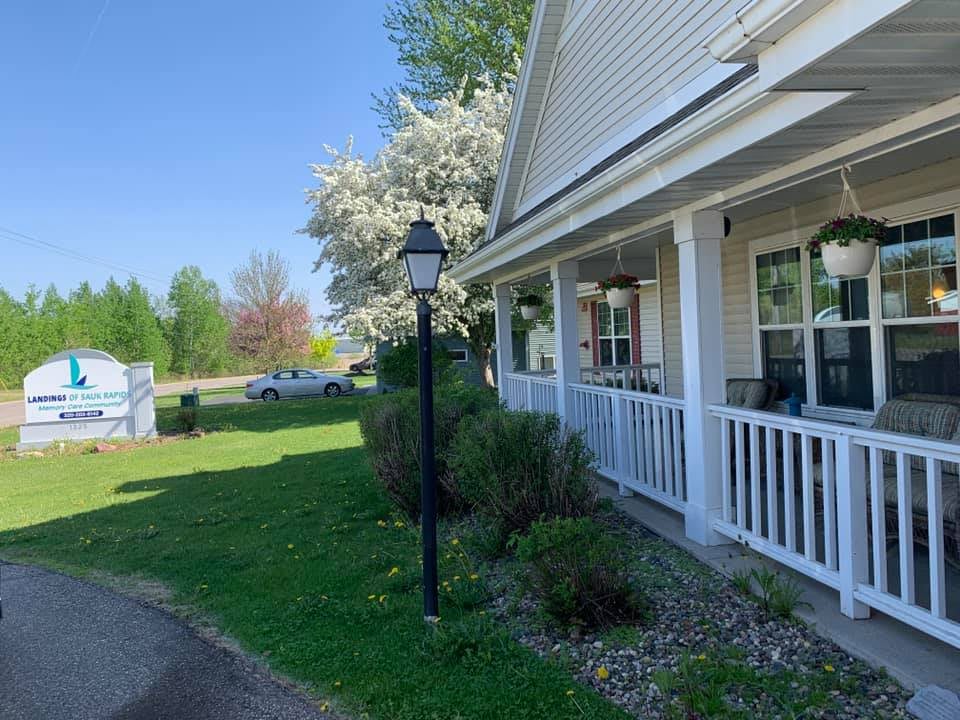 A charming house with a front porch and blooming trees on a sunny day.