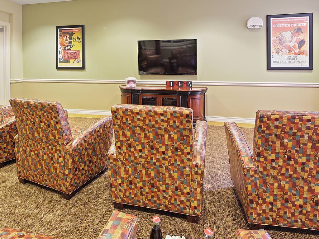 A cozy living room setup with patterned chairs facing a wall-mounted television.